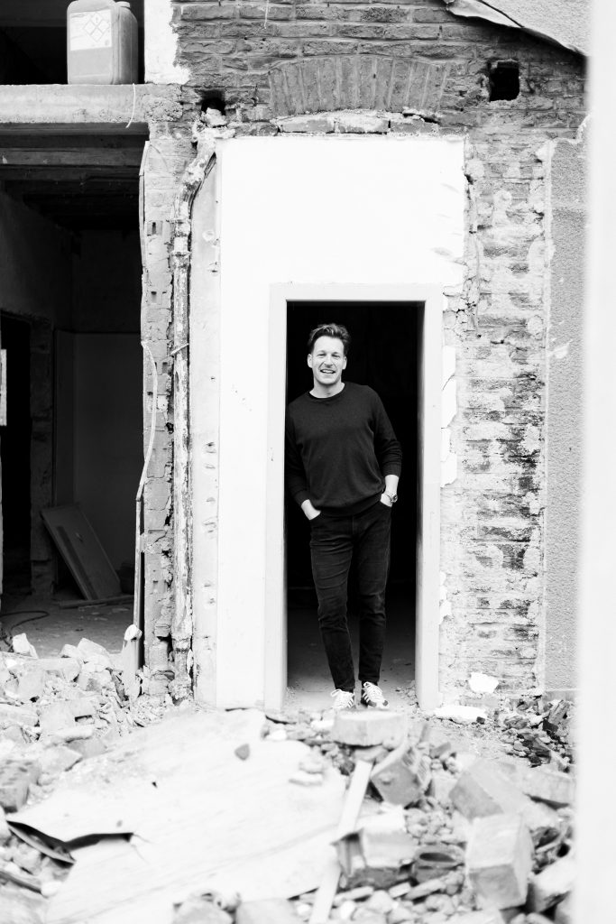 Energieberater Claudius Kremer steht in der Tür einer halb abgerissenen Baustelle – authentisches Portrait Sauerland