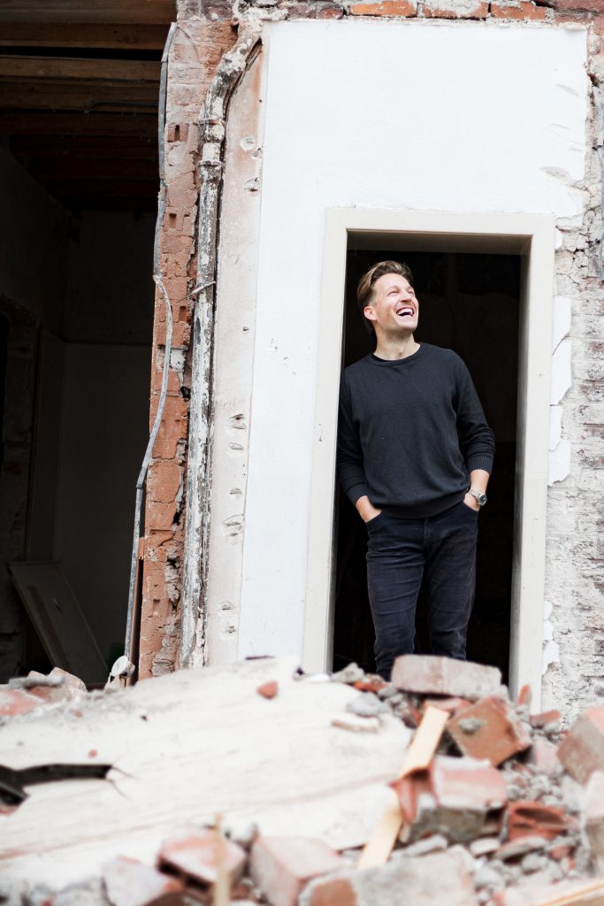 Energieberater Claudius Kremer steht in der Tür einer halb abgerissenen Baustelle – authentisches Portrait Sauerland