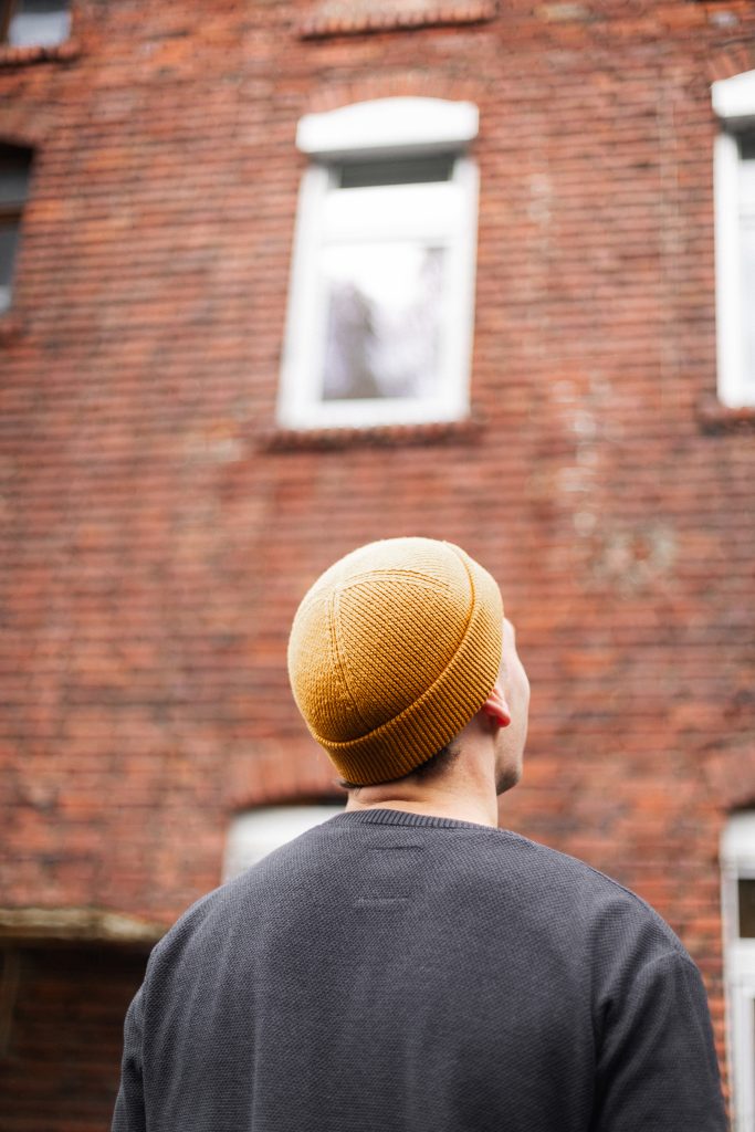 Claudius Kremer trägt Beanie und steht vor dem Backsteinhaus auf der Baustelle – Outdoor Portraitshooting Grevenbrück