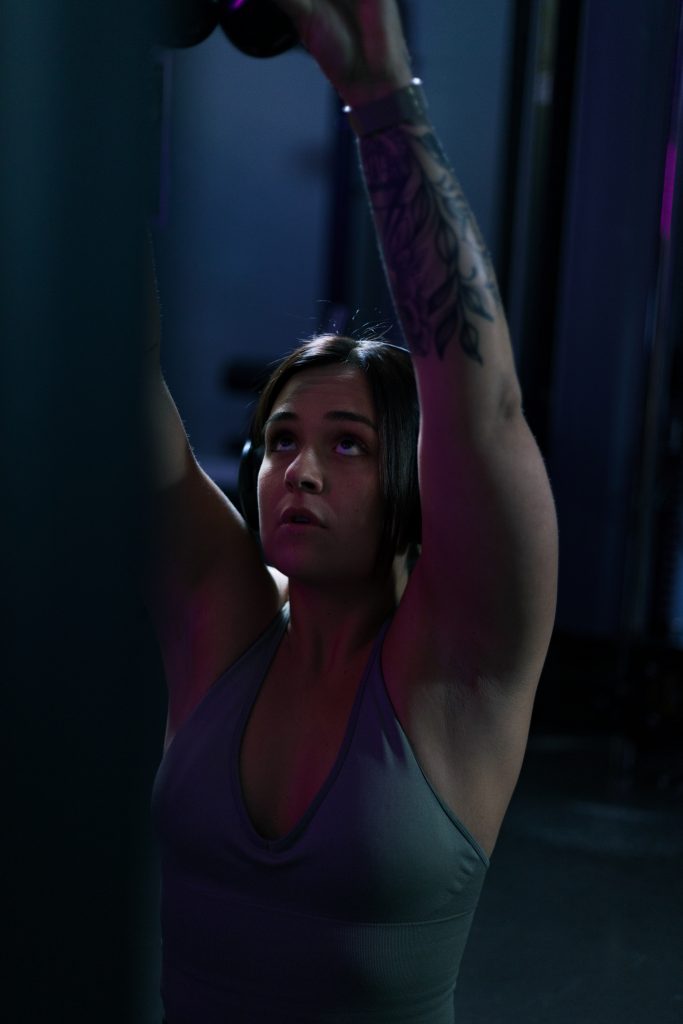 Authentisches Fitnessporträt in industrieller Umgebung mit kreativer Lichtsetzung.