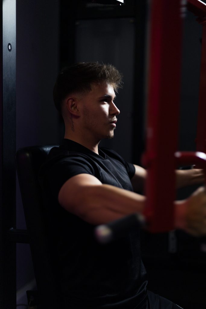 Authentisches Fitnessporträt in industrieller Umgebung mit kreativer Lichtsetzung.