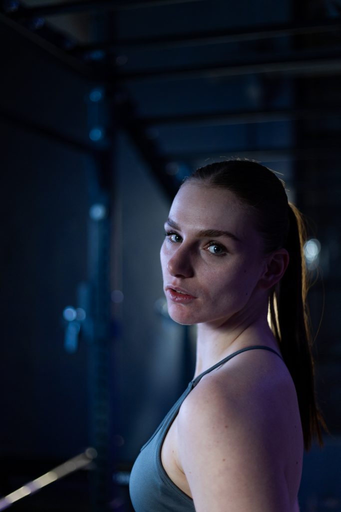 Authentisches Fitnessporträt in industrieller Umgebung mit kreativer Lichtsetzung.